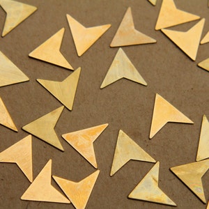 May include: A collection of gold-coloured metal arrow shapes scattered on a brown surface.
