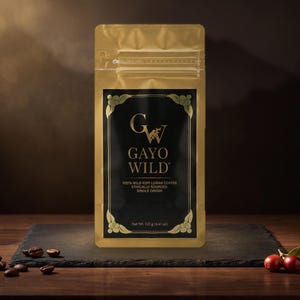 May include: A gold-coloured coffee pouch with a black rectangular label featuring the text GAYO WILD, 100% WILD KOPI LUWAK COFFEE, ETHICALLY SOURCED, SINGLE ORIGIN, and Net Wt. 125 g (4.41 oz) in gold lettering with decorative corner accents.