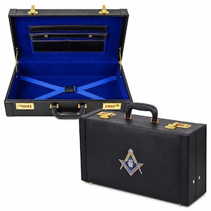 May include: A black briefcase with gold-tone hardware and combination locks. The exterior features a square and compass emblem. The interior is lined in bright blue fabric with black organizational pockets and blue elastic straps.