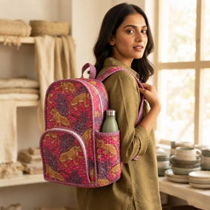 May include: A quilted backpack in a vibrant magenta pink fabric featuring a repeating pattern of yellow and black leopards amidst dark blue foliage. The bag includes a top handle, adjustable shoulder straps, and a side pocket holding a bottle.