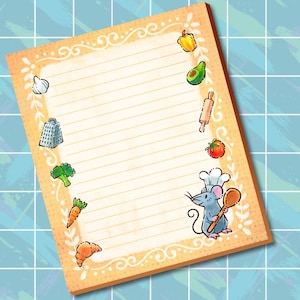 May include: A rectangular notepad with lined paper and a tan border featuring white decorative swirls. The border is decorated with illustrations of a garlic bulb, grater, broccoli, carrot, croissant, yellow pepper, avocado, rolling pin, tomato, and a mouse chef.