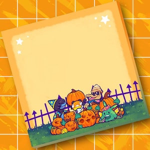 May include: A square notepad with a light orange border and a blank center featuring a bottom illustration of cartoon characters in costumes, including a wizard, a mummy, and a creature with a flower crown, surrounded by carved pumpkins.