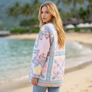 May include: A quilted jacket featuring a patchwork design with light blue, pink, and yellow fabric squares, floral patterns, and gingham accents. The jacket has a collarless neckline, long sleeves, and a straight hem, paired with light blue denim jeans.