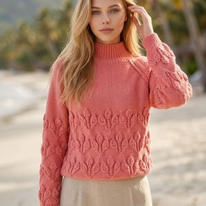 May include: A coral-colored long-sleeve knit sweater featuring a high mock neck collar and a textured leaf-patterned design across the front and sleeves, paired with a plain beige skirt made of a smooth, woven fabric material.
