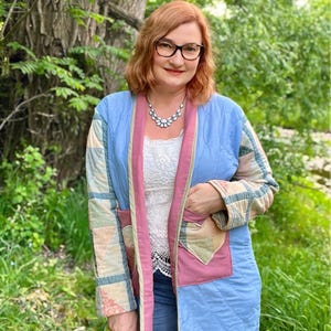 Peut inclure: Veste matelassée bleu clair avec bordure rose et manches patchwork. La veste a des poches et est portée sur un haut en dentelle blanche. Le style général est bohème et fait main.