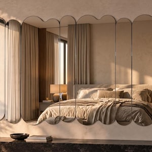 May include: A large wall mirror composed of eight vertical, wavy-edged panels arranged side-by-side. The reflective glass panels feature rounded top and bottom edges, creating a continuous, fluid, and scalloped silhouette across the wall.
