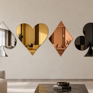 May include: A set of four wall-mounted mirrors shaped like playing card suits. The spade is silver, the heart is gold, the diamond is copper, and the club is black. Each mirror reflects the surrounding room, creating a decorative display.