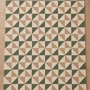Peut inclure: Un jeté au crochet rectangulaire présentant un motif de moulin à vent répétitif en vert olive, beige et crème. Le texte Meadow Pinwheel Throw Crochet pattern US terms est visible en haut, et Design concept Physical sample pending en bas.