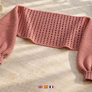 May include: A dusty rose crochet shrug featuring a wide, open-knit rectangular center panel and long, voluminous sleeves with ribbed cuffs. The garment is crafted from a textured yarn, showcasing a consistent stitch pattern throughout the design.