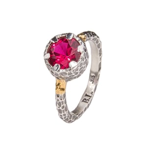 May include: A silver ring with a textured band and a gold accent. The ring features a large, round, bright pink gemstone set in a textured bezel. The ring is marked with "B.L. 925".