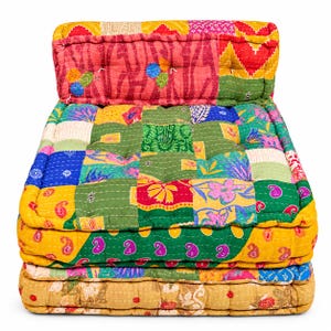 May include: A floor cushion chair featuring a patchwork design made from various colorful fabrics in shades of yellow, green, red, and blue. The surface is quilted with visible white stitching and includes a backrest section and a thick seat base.