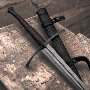 May include: A longsword with a dark brown wrapped grip, a black crossguard, and a patterned steel blade featuring a central fuller. The sword is accompanied by a black leather scabbard embossed with a griffin emblem and equipped with straps.