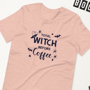 May include: A pink heather t-shirt with a black graphic that says "Total Witch Before Coffee" with a witch's hat, bats, and a spider.