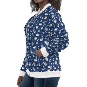 May include: A blue bomber jacket with a white and blue pattern of teacups and teapots. The jacket has a white ribbed collar, cuffs, and hem.