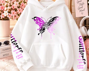 May include: A white hooded sweatshirt featuring a large butterfly graphic on the chest with a purple and black gradient. The word BUTTERFLY is printed in a purple and black gradient on both sleeves. The hoodie includes a front kangaroo pocket.