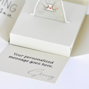 May include: A white pop-up card with a small white bear holding a red heart. The card is open and the inside reads "Your personalized message goes here." and is signed "Stacey".