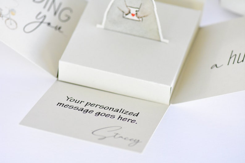 May include: A white pop-up card with a small white bear holding a red heart. The card is open and the inside reads "Your personalized message goes here." and is signed "Stacey".