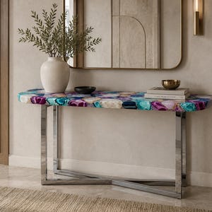 May include: A console table featuring a polished chrome metal base with an X-shaped support and a rectangular top inlaid with multicolored agate slices in shades of vibrant purple, teal, blue, and white, creating a natural stone pattern.