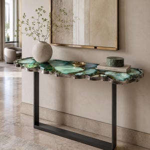 May include: A console table featuring a polished, irregular-shaped top made of translucent green and blue agate slices with a metallic edge. The table is supported by a black metal frame with two vertical legs connected by a horizontal base bar.