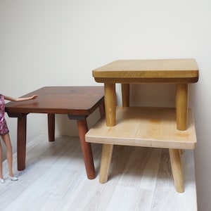 Könnte beinhalten: Zwei Holztische, die übereinander gestapelt sind. Der obere Tisch ist hellbraun und der untere Tisch ist dunkelbraun. Die Tische haben jeweils vier Beine.