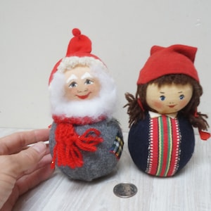 Op de afbeelding: Twee vintage kerstversieringen, een is een grijze en rode kerstman met een witte baard en de andere is een rode en blauwe elf met bruin haar.