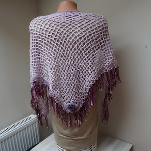 May include: A light purple crochet shawl with a fringe border. The shawl is made of a delicate, open-weave fabric and has a subtle ombre effect.