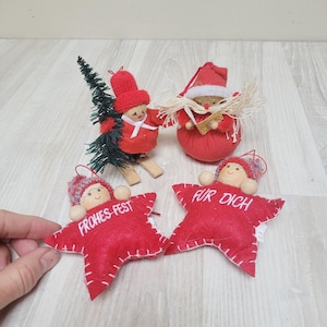 Op de afbeelding: Kerstversieringen met rode vilten sterren met de teksten "FROHES-FEST" en "FÜR DICH". Andere ornamenten zijn een rode kerstmanfiguur, een figuur met een groene kerstboom en een figuur op ski's.