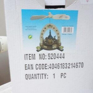 May include: A white cardboard box with a picture of a wooden Christmas pyramid with a star on top. The box has the text "ITEM NO: 520444", "EAN CODE: 4046183214670", and "QUANTITY: 1 PC" printed on it.