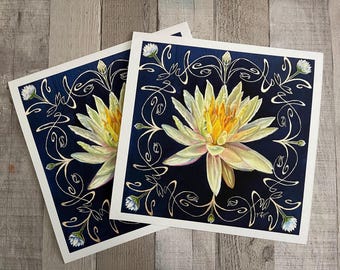 Könnte beinhalten: Zwei Drucke einer weißen Seerose mit gelber Mitte auf dunkelblauem Hintergrund. Die Seerose ist von einem goldenen, wirbelnden Design umgeben.