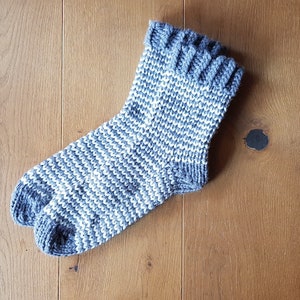 May include: A gray and white striped knitted sock with a folded cuff.