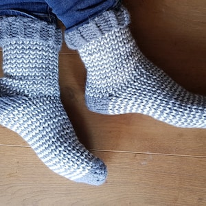 May include: A pair of gray and white striped knitted socks with a fold-over cuff.