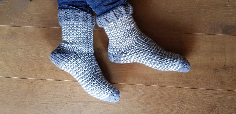 May include: A pair of gray and white striped knitted socks with a fold-over cuff.