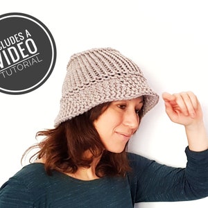 Puede incluir: Una mujer lleva un sombrero de cubo de punto de color marrón claro. El sombrero tiene un ala ancha y una textura acanalada. La imagen incluye un círculo con el texto "Includes a Video Tutorial".