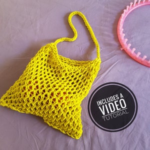 Könnte beinhalten: Eine leuchtend gelbe gehäkelte Tragetasche mit einem langen Riemen. Die Tasche ist mit einem einfachen Stichmuster gearbeitet und hat eine lockere, offene Maschenstruktur. Das Bild enthält den Text "Includes a Video Tutorial".