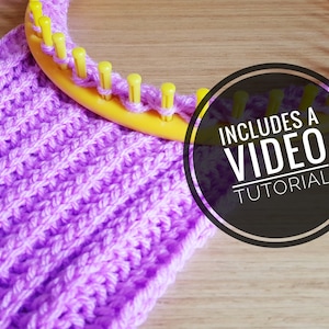 May include: A purple knitted scarf is being made on a yellow knitting loom. The loom is partially wrapped around the scarf. The text "INCLUDES A VIDEO TUTORIAL" is in a black circle.