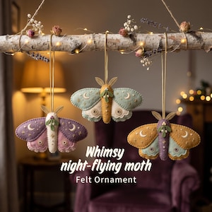May include: Three felt moth ornaments hanging from a birch branch. Each moth features embroidered moon, star, and circular patterns. The moths are colored in purple and pink, light blue and yellow, and yellow and purple. Text reads: Whimsy night-flying moth Felt Ornament.