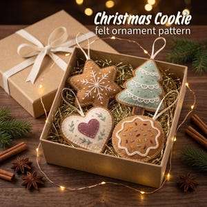 May include: A set of four felt ornaments in a cardboard box, including a brown star with white stitching, a light green tree, a white heart with a purple center, and a brown round cookie with colorful sprinkles, labeled Christmas Cookie felt ornament pattern.
