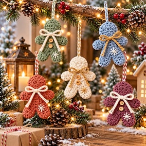 May include: Five crocheted gingerbread-style ornaments in sage green, light blue, cream, terracotta, and plum. Each figure features a yarn bow, two small wooden buttons, and a stitched snowflake detail, suspended by a decorative hanging loop.