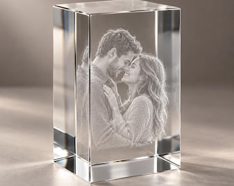 May include: A rectangular clear glass block featuring a three-dimensional laser-etched image of two people embracing. The internal engraving captures the detailed profiles of the individuals as they face each other in a close, affectionate pose.