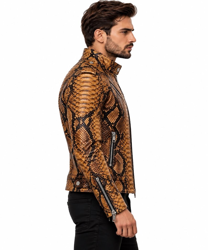 K&ouml;nnte beinhalten: Eine Jacke mit braun-schwarzem Schlangenledermuster, Stehkragen, silberfarbenen Metallrei&szlig;verschl&uuml;ssen an der Vorderseite und an den &Auml;rmelb&uuml;ndchen sowie Druckknopfdetails an Schultern und Saum, getragen &uuml;ber einer schwarzen Hose.