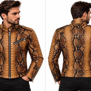 K&ouml;nnte beinhalten: Eine Jacke mit Schlangenledermuster in Beige und Schwarz, ausgestattet mit einem Stehkragen, einem zentralen silberfarbenen Rei&szlig;verschluss, zwei schr&auml;gen Brust- und Seitentaschen mit Rei&szlig;verschl&uuml;ssen sowie Rei&szlig;verschl&uuml;ssen an den &Auml;rmelb&uuml;ndchen.
