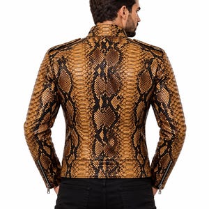 K&ouml;nnte beinhalten: Eine lang&auml;rmelige Jacke mit einem markanten Schlangenledermuster in Braun und Schwarz. Das Kleidungsst&uuml;ck verf&uuml;gt &uuml;ber einen Stehkragen, Schulterklappen und silberfarbene Metallrei&szlig;verschl&uuml;sse an den &Auml;rmelb&uuml;ndchen, dargestellt in der R&uuml;ckansicht.