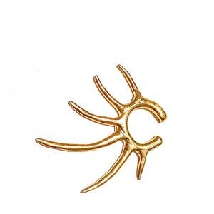 May include: A gold-colored ear cuff in the shape of antlers, with multiple curved tines extending from a central ring. The jewelry piece is set against a white background, highlighting its intricate design and metallic finish.