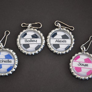 May include: Four zipper pulls with personalized soccer ball designs. The names "Bailey", "Alexis", "Michelle", and "Joye" are printed on the pulls.