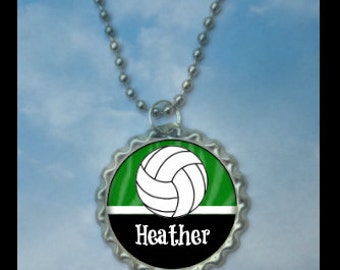 May include: Silver bottle cap necklace with a green and black design. A white volleyball is in the center of the green portion. The name "Heather" is printed in white on the black portion.