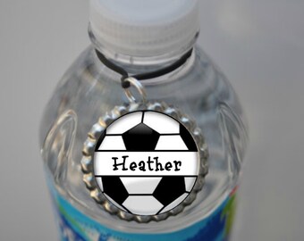 May include: A clear plastic water bottle with a black and white soccer ball charm attached. The charm has the name "Heather" written on it.