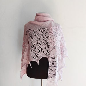 May include: A delicate pink lace shawl with a scalloped edge, draped over a black mannequin.