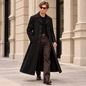 May include: A long black trench coat worn over a black t-shirt and dark brown trousers. The outfit includes a dark brown leather belt, black leather dress shoes, and dark-tinted sunglasses. The coat features a classic collar and button closure.