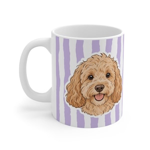May include: A white ceramic mug featuring a vertical lavender and white striped pattern. Centered on the mug is a detailed illustration of a light brown, curly-haired dog with dark eyes and a pink tongue, depicted in a friendly, smiling expression.
