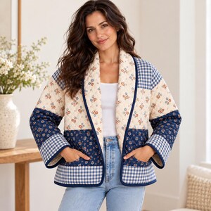 K&ouml;nnte beinhalten: Eine gesteppte Jacke mit einem Patchwork-Design aus cremefarbenem Stoff mit kleinen Blumenmustern, dunkelblauem Stoff mit Blumenmotiven sowie blau-wei&szlig; karierten Gingham-Abschnitten. Die Jacke hat lange &Auml;rmel, einen Schalkragen und zwei Taschen.